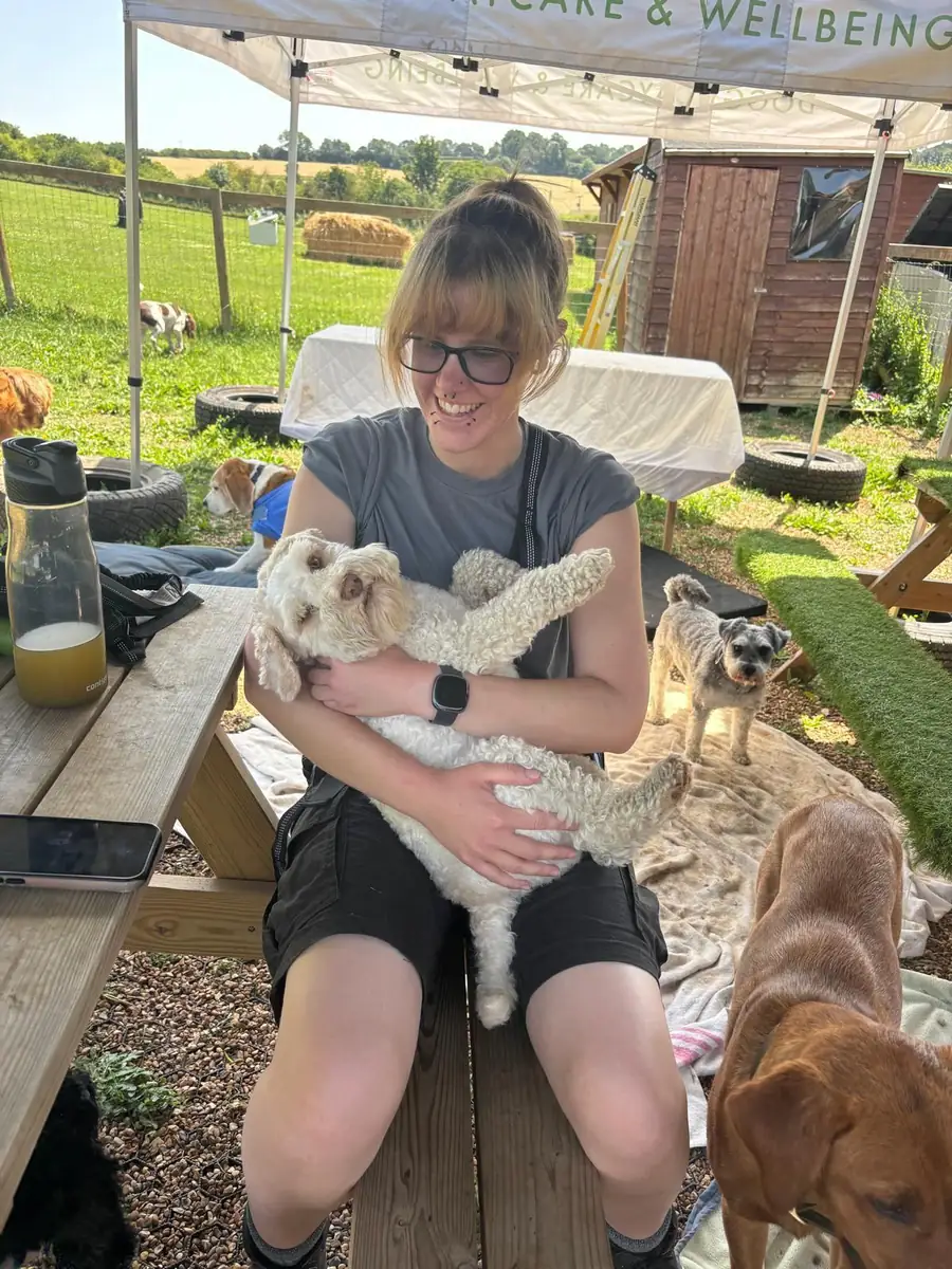 A Schnoodles team member cuddling a cockapoo under the Schnoodles gazebo